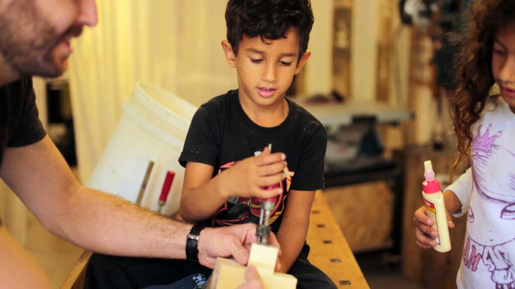 ילד מדביק עצים בנגרות